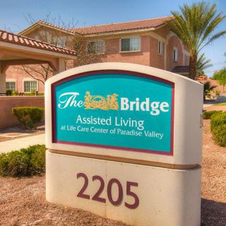 The exterior sign of The Bridge Assisted Living facility displays its name and address.