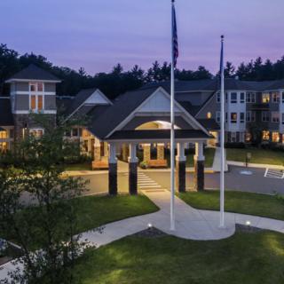 A well-lit building with flags displayed at dusk.