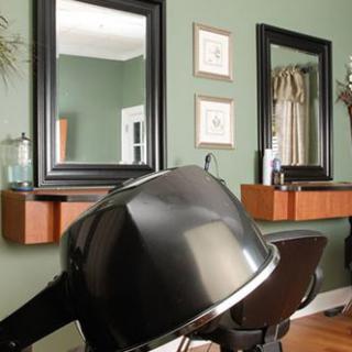 A modern salon interior featuring hair drying equipment and large mirrors.