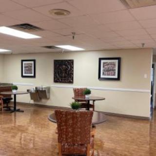 A small cafeteria area with tables, chairs, and wall art.