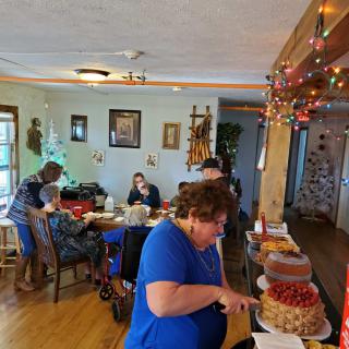 A family gathering with people enjoying food and cake in a decorated dining room.