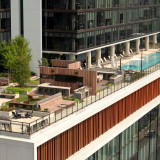 A modern rooftop featuring a pool, green spaces, and outdoor seating in an urban setting.