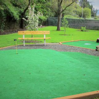 A serene outdoor mini golf course with a bench for relaxation.