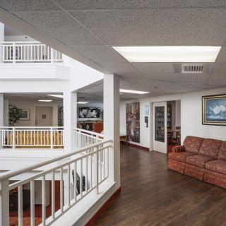 A modern interior hallway with seating and artwork, featuring wood flooring and railings.