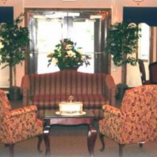 A cozy lobby area with a sofa, two chairs, and a central table adorned with plants.