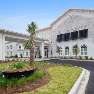 A modern residential building with landscaped surroundings and palm trees.