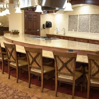 A modern kitchen with a large countertop and wooden bar stools.