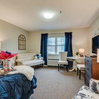 A cozy and well-decorated living space featuring a bed, sofa, table with chairs, and a television.