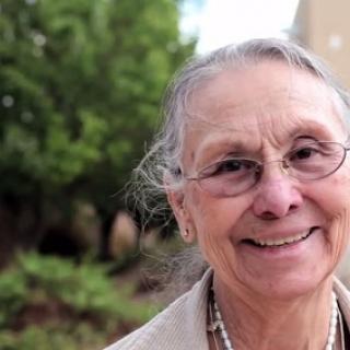 A joyful older woman enjoying the outdoors with a warm smile.