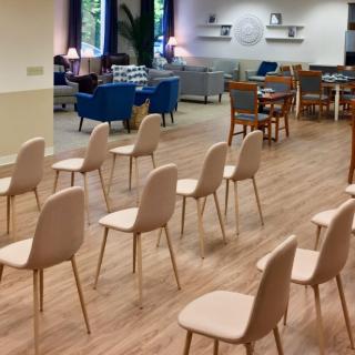An empty meeting room with neatly arranged chairs and a cozy seating area in the background.