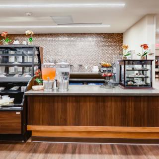 A modern cafe counter with a variety of beverages and food displays.
