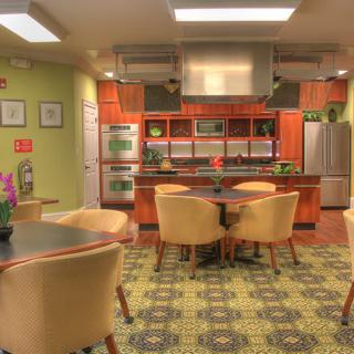 A modern kitchen and dining area with wooden cabinetry, stainless steel appliances, and comfortable seating.