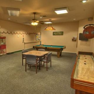 A cozy game room featuring a pool table, shuffleboard, and a table with chairs.