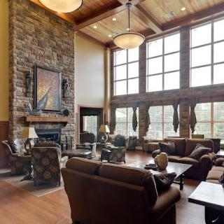 A spacious living room with a stone fireplace, large windows, and comfortable seating.