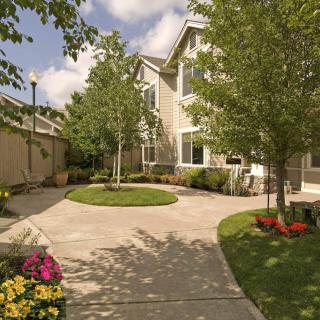 A well-maintained house with a driveway surrounded by trees and colorful flowers.