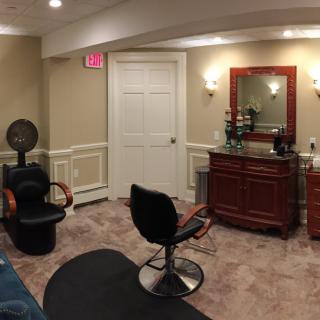 A cozy hair salon with styling chairs and a mirror.