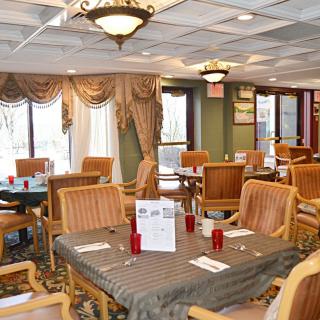 An elegant dining area with neatly arranged tables and chairs, decorated with chandeliers and drapes.