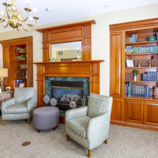 A cozy library with wooden bookshelves, a fireplace, and comfortable armchairs.