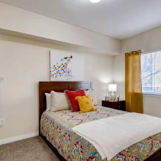 A cozy bedroom with a neatly made bed, colorful pillows, and wall art.