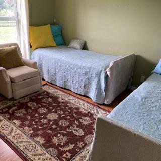 A cozy bedroom with two twin beds, a chair, and a decorative rug.