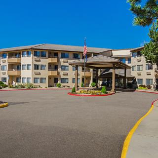 A multi-story apartment complex with a spacious driveway and well-maintained landscaping.
