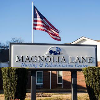Entrance sign for Magnolia Lane Nursing & Rehabilitation Center, with an American flag waving in the background.