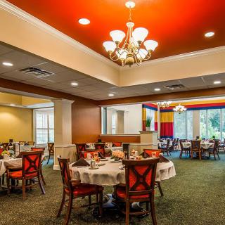 An elegant restaurant dining room with neatly arranged tables and a beautiful chandelier overhead.