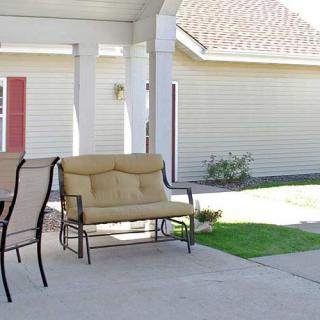 A cozy patio area with a swing bench and chairs under a covered space in the backyard.