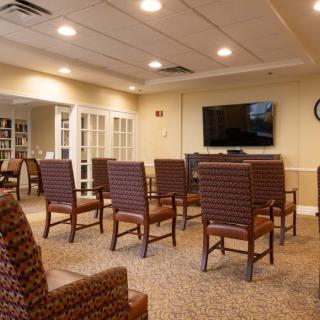 A well-lit conference room with several chairs arranged facing a large television.