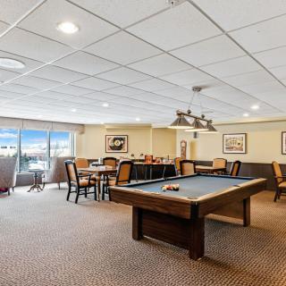 A spacious game room featuring a pool table and seating area.