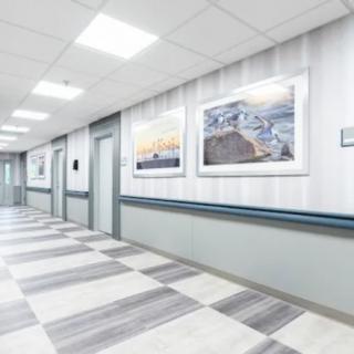 A clean and modern hospital corridor with framed artwork on the walls.