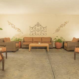 A cozy outdoor seating area with wicker furniture and decorative wall art.