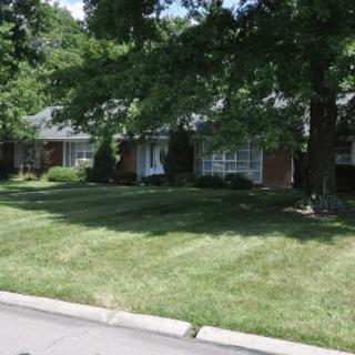 A suburban house with a well-maintained lawn and trees.