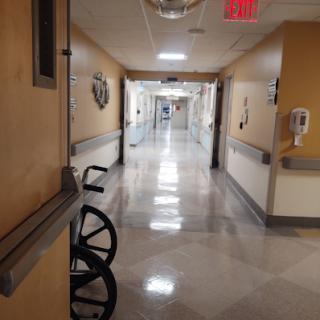 A quiet corridor in a hospital, featuring a wheelchair parked along the wall.