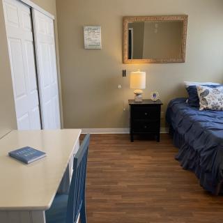 A cozy bedroom with a neatly made bed, nightstand, and mirror above.