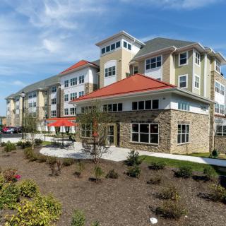 A modern apartment complex with landscaped surroundings under a clear blue sky.