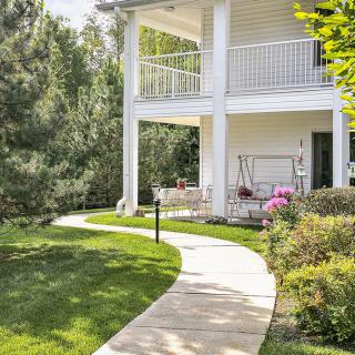 A charming house with a wrap-around porch and landscaped garden path.
