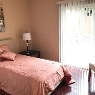 A cozy bedroom with a single bed, nightstand, and sliding doors leading outside.