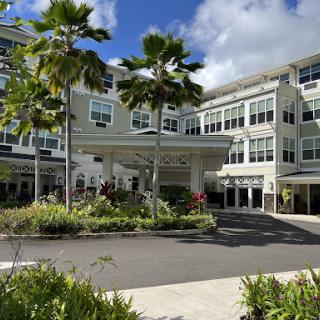 A modern hotel entrance surrounded by lush landscaping and palm trees.