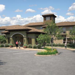 An elegant building with an arched entrance surrounded by landscaped greenery.
