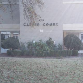 A view of the building with a sign that reads 'CARRIE COURT' surrounded by well-kept landscaping.