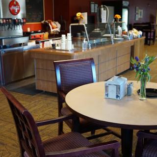 A cozy caf interior featuring a coffee station, wooden furniture, and a touch of greenery on the table.
