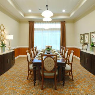 An elegantly furnished dining room with a long table and upholstered chairs set for a formal meal.