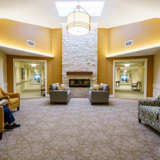 A modern lounge area featuring comfortable seating around a central fireplace.