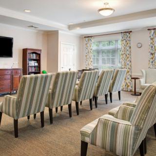 A neatly arranged meeting room with striped chairs, a television, and a bookshelf.