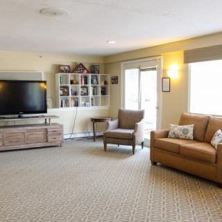 A cozy living room with a sofa, armchair, and a large television.