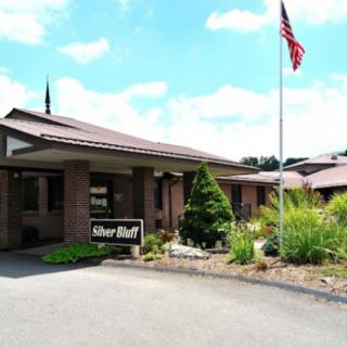 A building entrance with an American flag and landscaped surroundings.