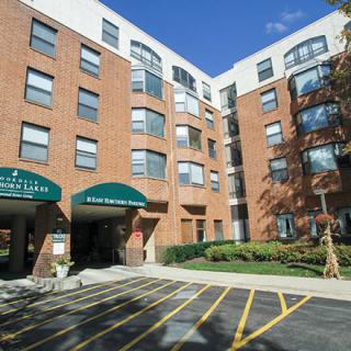 A modern urban apartment building with a brick exterior and green awnings.