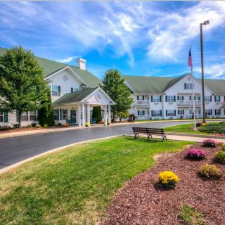 A picturesque view of a large building with a welcoming entrance, surrounded by well-maintained gardens and under a vibrant blue sky.