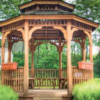 A wooden gazebo surrounded by lush greenery.
